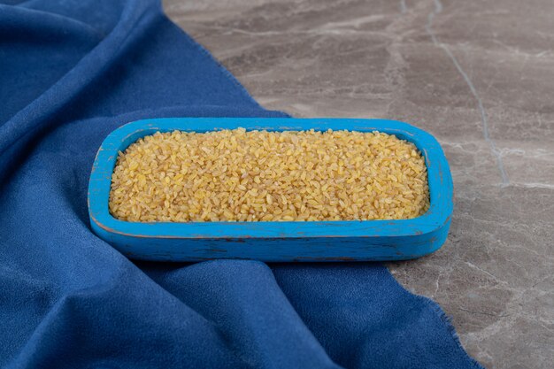 Bulgur in het dienblad op de handdoek op het marmeren oppervlak