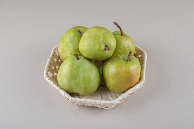 Bundel van peren in een witte mand op marmer