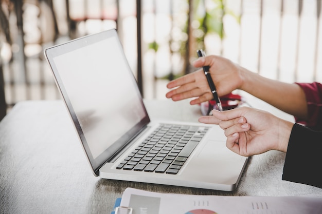 Business analyse concept. De onderneemster die bedrijfsdocumenten, finacial rapport analyseren, die aan laptop computer, mobiele slimme telefoon aan bureau werken, sluit omhoog.