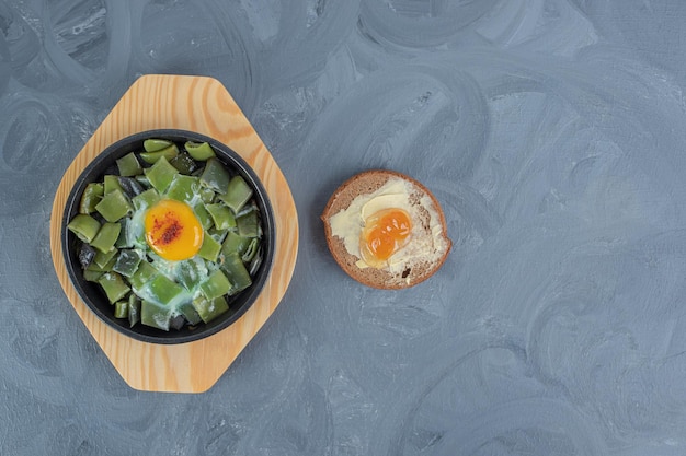 Butterbrot naast een kleine schotel van gehakte bonenpulsen met ei-topping op marmeren achtergrond.