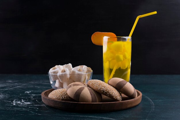 Cacao en vanille koekjesbroodjes met lokum en een glas sap in houten schotel