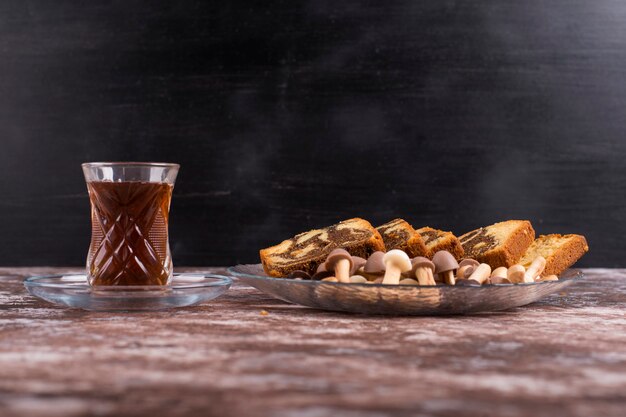 Cacaocake met wafels en koekjes in een glazen schotel met een glas thee