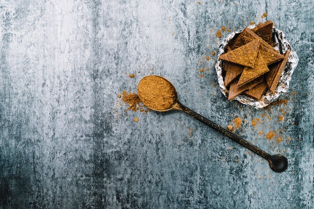 Cacaopoeder en chocoladestukjes in kom op oude concrete achtergrond