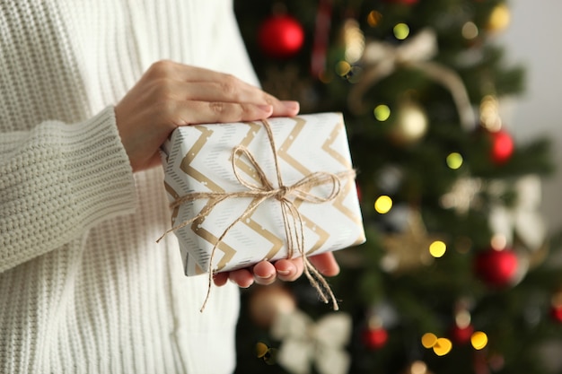 Cadeau in handen voor kerstmis of nieuwjaar op een achtergrond van een versierd interieur Premium Foto