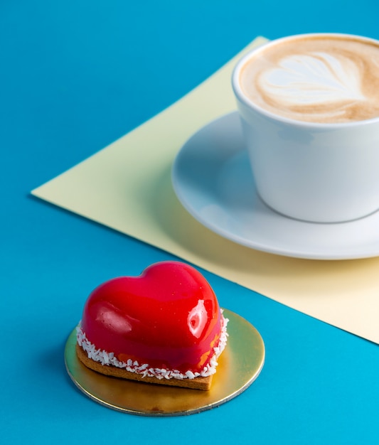 Gratis foto cake hartvormige mousse cake op blauw met kopje koffie