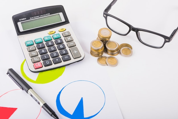 Calculator met munten stapels op tafel