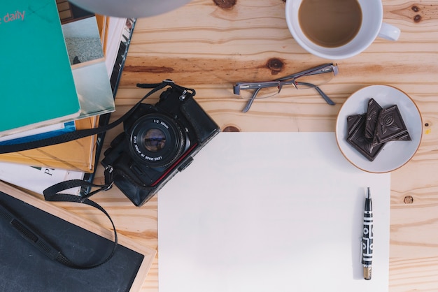 Gratis foto camera en glazen dichtbij document blad en snack