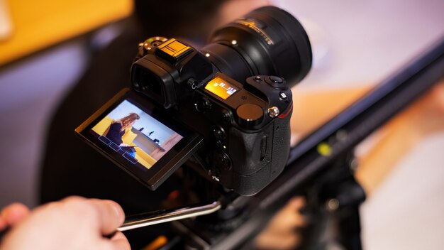 Camera op een statief die een jong meisje met tablet op bank fotografeert. Werken vanuit huis