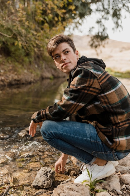 Camping man in het bos zit aan het zijaanzicht van de rivier