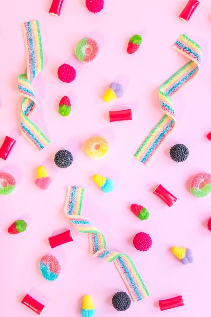 Gratis Foto candies verspreid over roze tafel