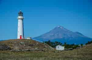 Gratis foto cape egmont lighthouse met de berg taranaki erachter in pungarehu, nieuw-zeeland