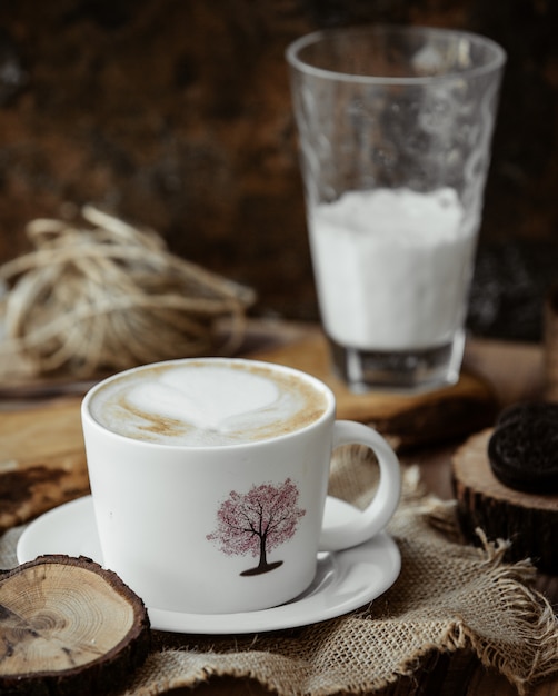 Cappuccinokop en glas melk op de lijst