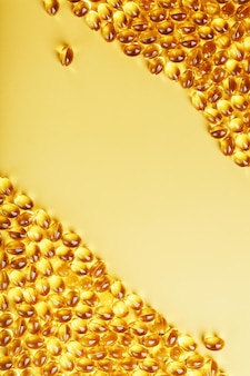 Capsules in een schaal met vloeibare vitamine d3 op een gele achtergrond en een plek voor tekst gouden capsules met een biologisch actief supplement voor gewrichten, tanden en botten