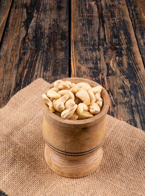 Cashew in een houten kop zijaanzicht op een stuk zak