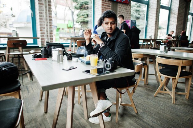 Casual en stijlvolle jonge Aziatische man met koptelefoon in café sushi eten