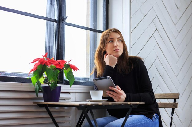 Casual vrouw koffie drinken en werken met tablet pc.