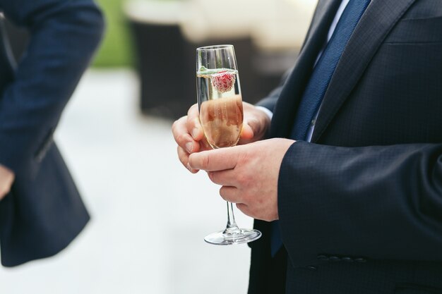 Champagnefluit in het bezit van een man in een zwart jasje