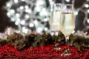 Gratis foto champagneglazen met kerstverlichting op de achtergrond