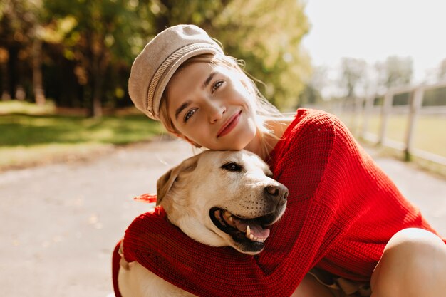 Charmant meisje en haar hond met een goede tijd in het najaar park. Mooie blonde met mooie hond poseren.