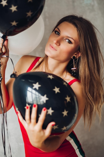 Gratis foto charmant model in rode jurk poseren met ballonnen