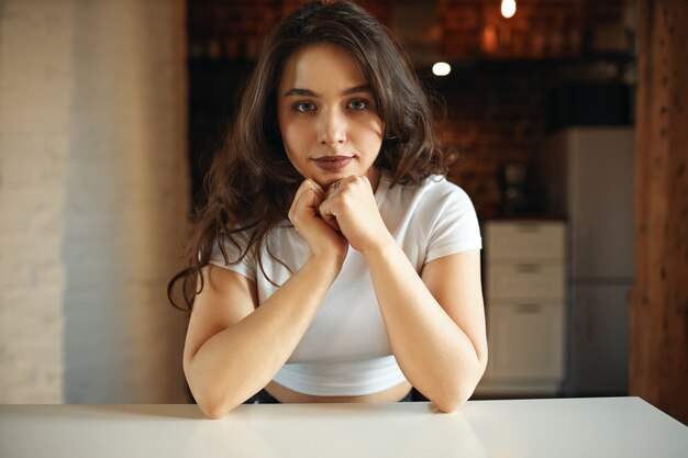 Charmant mooi studentenmeisje met lang losse haren aan tafel zitten