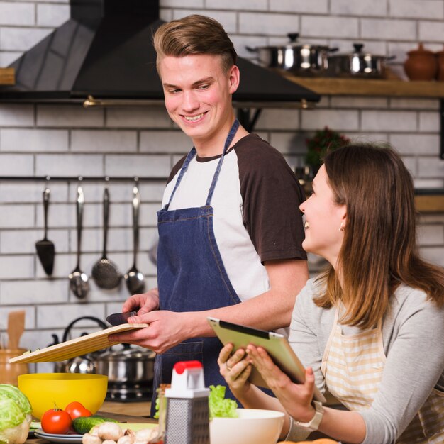 Charmant paar die tablet gebruiken aan het koken in keuken