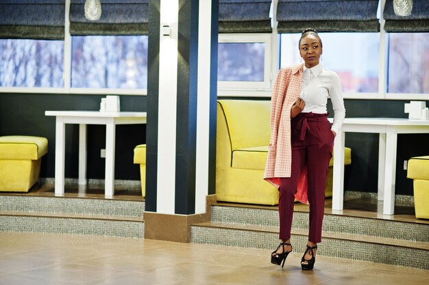 Charmante Afro-Amerikaanse vrouw in formele kleding poseren in restaurant