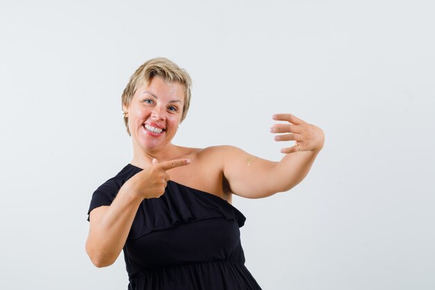 Charmante dame die zich voordeed als wijzend op de telefoon in een zwarte blouse en er tevreden uitziet