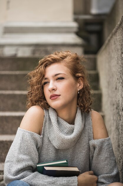 Charmante dame met kort krullend haar dat boeken houdt