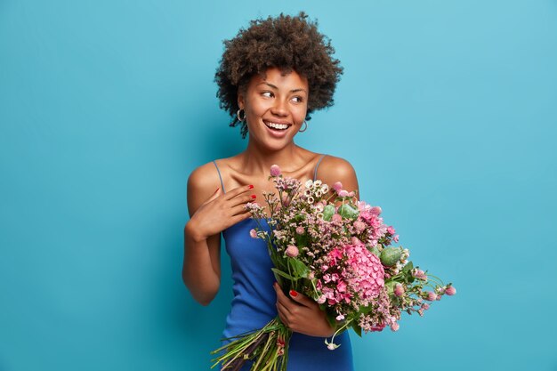 Charmante romantische mooie Afro-Amerikaanse vrouw houdt groot boeket ontvangt bloemen