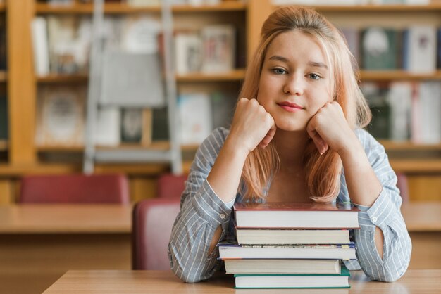 Charmante tiener zit in de buurt van boeken