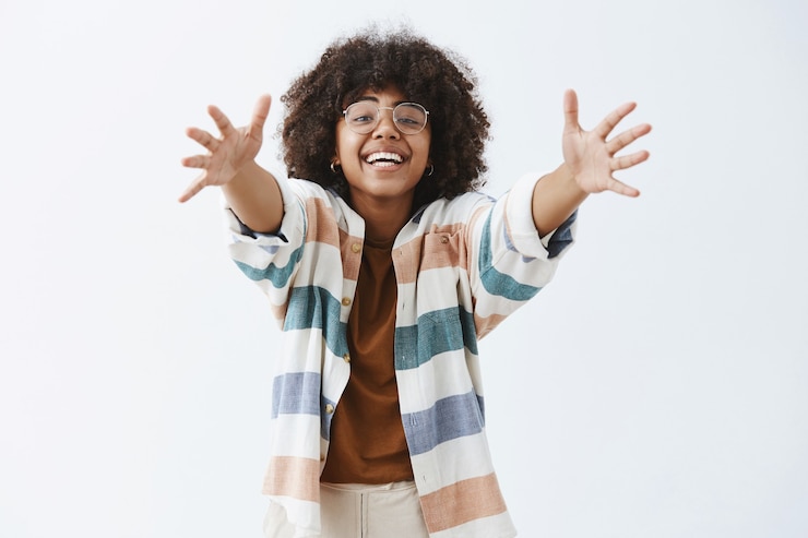Gratis Foto charmante vriendelijke en schattige afro-amerikaanse moderne vrouw in stijlvolle outfit handen trekken om knuffel te geven