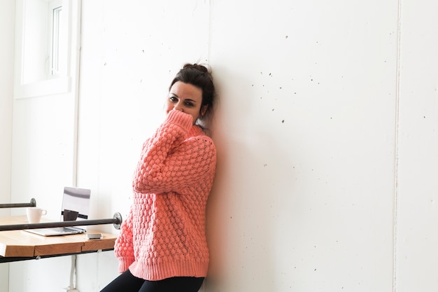 Gratis foto charmante vrouw in sweater die op muur leunt