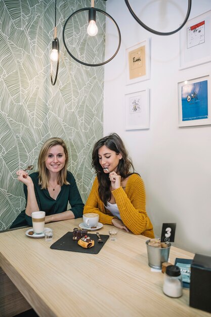 Charmante vrouwen die cake in koffie eten