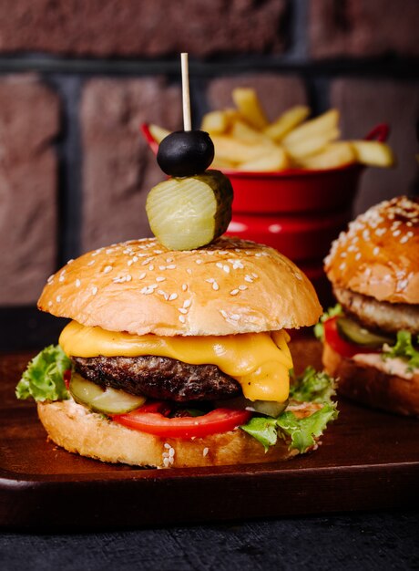 Cheeseburger in broodbroodje met olijven bovenop.