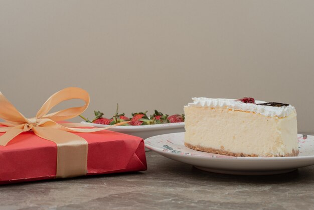 Cheesecake, aardbeien en een geschenkdoos op marmeren tafel.