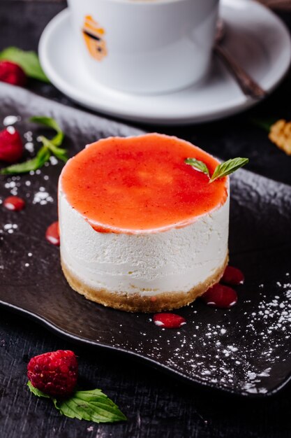 Cheesecake met frambozensiroop en muntblaadjes.