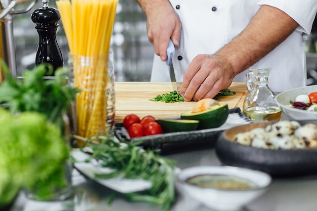 Chef-kok die de groente snijdt en salade voorbereidt.