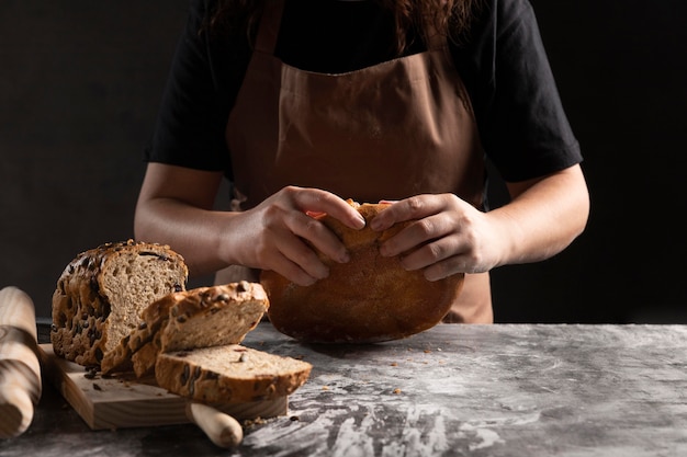 Gratis foto chef-kok die gebakken brood uit elkaar scheurt