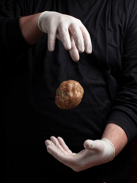 Chef-kok die in witte handschoenen vleesballen maakt