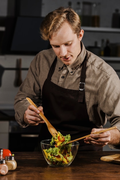 Gratis foto chef-kok die ingrediënten voor de salade mengt