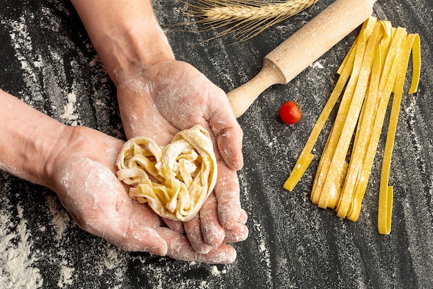 Chef-kok die ongekookte deegwaren in handen houdt