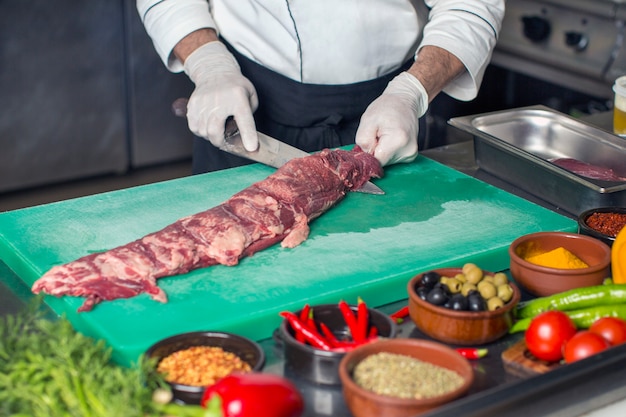 Chef-kok die ruwe rundvleeslapje vlees snijden van het midden in de keuken