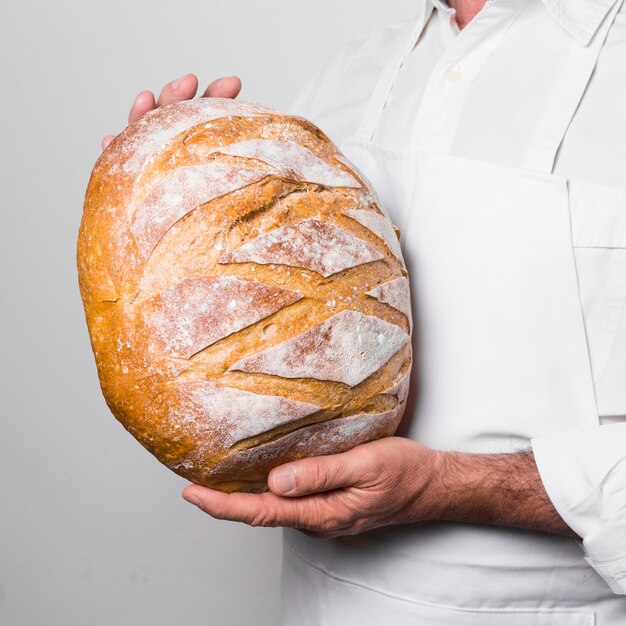 Chef-kok die witte kleren draagt die een warm brood houden