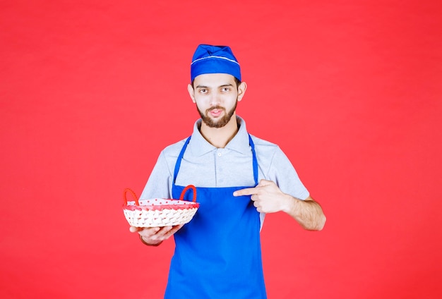 Chef-kok in blauwe schort met een broodmand bedekt met rode handdoek.