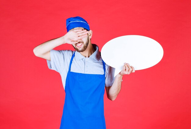 Chef-kok in blauwe schort met een ovale infobord en hoofdpijn.