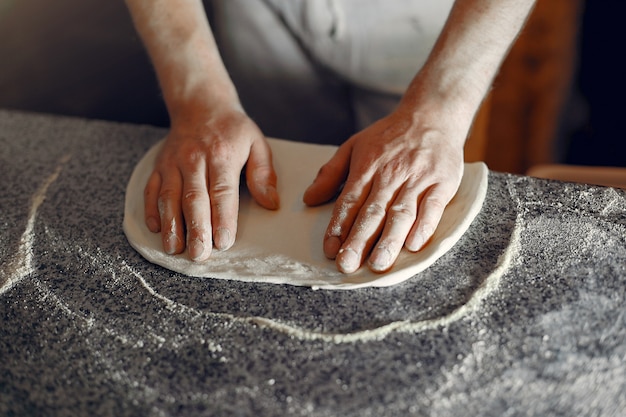 Chef-kok in een witte uniform bereiden een pizzaa