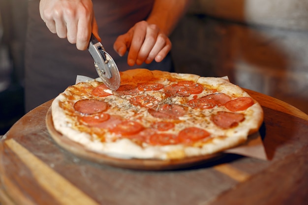 Chef-kok in een witte uniform bereiden een pizzaa