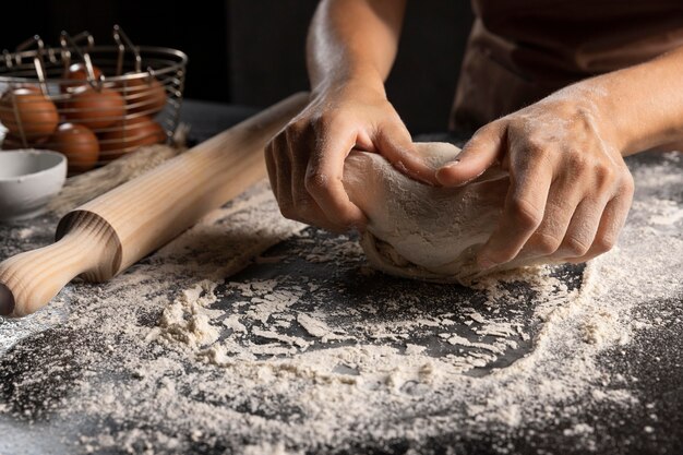 Chef-kok kneedt het deeg in bloem op tafel