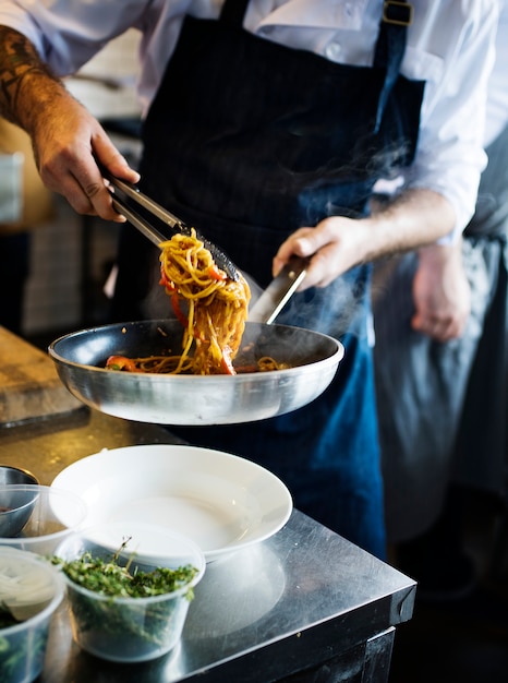 Gratis foto chef-kok kokende spaghetti in de keuken